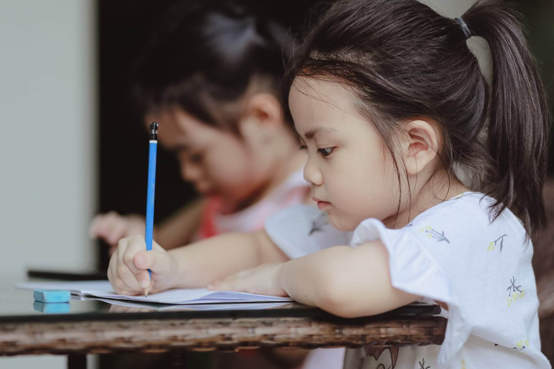 cute concentrated preschool girls doing homework in room
